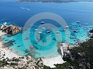 Picturesque beach with a line of boats moored at the water's edge in Sardinia, Italy.