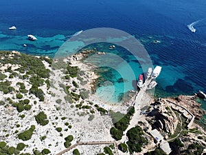 Picturesque beach with a line of boats moored at the water's edge in Sardinia, Italy.