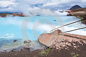 Picturesque blue hot geothermal lake in the evening. Big rock on the foreground.