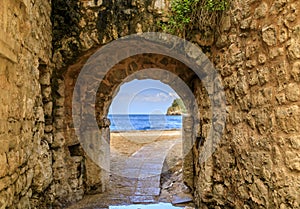 Picturesque brick arch and path of the medieval Old town open onto the Adriatic Sea in the Balkans in Budva, Montenegro