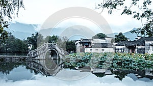 Picturesque bridge spanning across a tranquil body of water: Hongcun, China