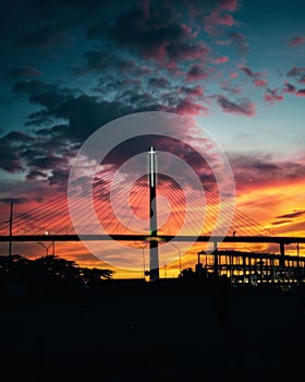 a bridge going across a river with a sunset in the background