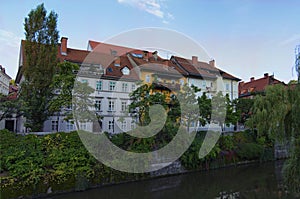 Picturesque cityscape view of Ljubljana. Embankment of Ljubljanica River with ancient colorful buildings against blue sky