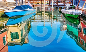 Picturesque colorful idyllic scene with a boat docked on the water canals in Burano Venice Italy. Water reflection