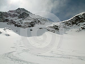 Picturesque deep winter mountain landscape in the Alps of Switzerland with backcountry ski tracks in fresh powder