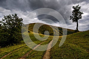 Malebná poľná cesta na pozadí kopca a zamračenej oblohy. Veľká Fatra, Slovensko.