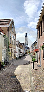 Picturesque dutch street with cathedral steeple and brick walk way.