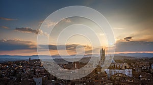 Picturesque epic backlit view of Siena Cathedral Santa Maria Assunta (Duomo) from Torre del Mangia tower at sunset golden hour,