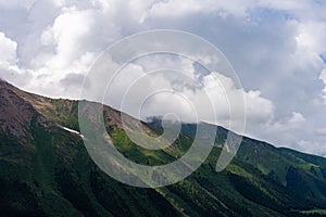 Picturesque, grassy valley surrounded by majestic, towering mountains with fluffy clouds above