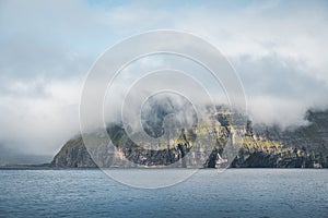 Picturesque green cliffs on Litla Dimun island and atlantic ocean in Faroe islands.