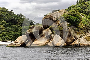 Picturesque huge granite boulders overgrown with tropical vegetation on the turquoise Atlantic ocean in Rio de Janeiro.