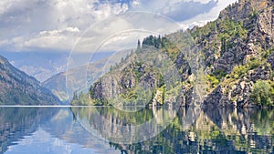 The picturesque lake of Sary Chelek. Amazing view of hills, mountains and rocks covered with green forests. The State Biosphere