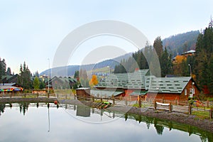 Picturesque lake and tourist houses in ukrainian ski Bukovel. Landscape with mountain lake in resort town