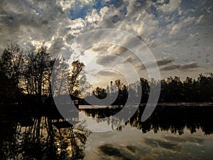 Picturesque lake underlined by silhouettes of trees at sunset