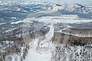 Picturesque landscape in the Altai mountains with snow-capped peaks under a blue sky with clouds in winter with gondola cableway