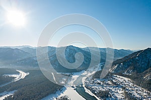 Picturesque landscape in the Altai mountains with snow-capped peaks under a blue sky with clouds in winter with green river and