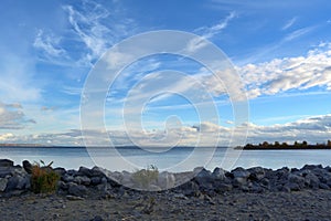 Picturesque landscape with blue river and grey stones on the bank. Beautiful sky panorama with clouds