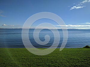 Picturesque landscape with green grass, blue sea and sky, Army Bay, New Zealand