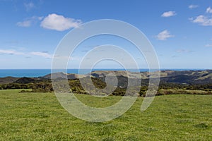 Picturesque landscape with green grass, hills and blue sea on background, Pae O Te Rangi farm track, New Zealand