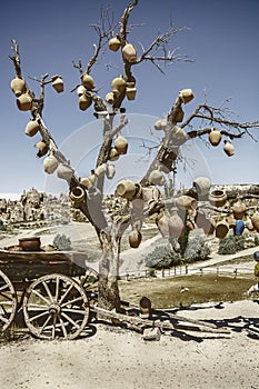 Picturesque landscape with jugs on a tree and old wagon full of clay pots