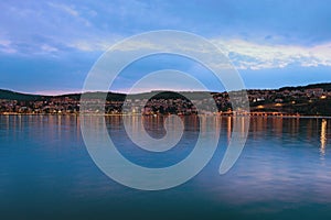 Picturesque landscape of Koper at night. Illumination of the city reflected in water of the Adriatic Sea