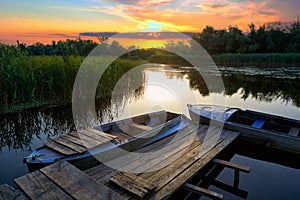 Picturesque landscape with an old rustic wooden pier and old boats at sunset on the Dnieper Delta