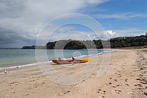 Picturesque landscape with orange kayak boat at white sand beach, Te Haruhi Bay at Shakespear Regional Park, New Zealand