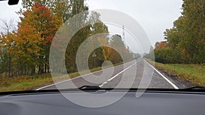 Picturesque landscape through the rain-drenched front window car. Bend in road. Road signs turning. Movement of windshield wipers