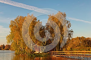 Picturesque landscape of small island with abandoned house and trees in the middle of the lake. Autumn morning landscape