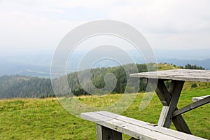 Picturesque landscape with wooden picnic table and mountain forest