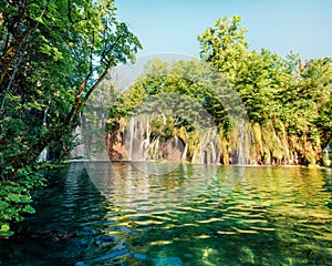 Picturesque morning csene of Plitvice National Park. Sunny spring view of green forest with pure water lake and waterfall. Great