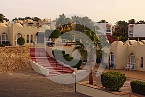 Picturesque morning view of hotel building of resort with palm trees and bushes during sunrise. Sharm El Sheikh, Egypt