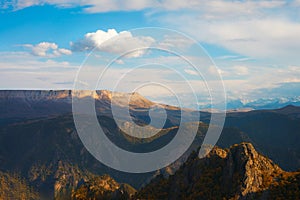 Picturesque mountain landscape with a rocky snow-capped ridge in the distance under a beautiful cloudy sky before sunset