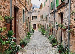 Picturesque Narrow Alley With Cozy Cottages And Green Pot Plants In Valldemossa On Balearic Island Mallorca