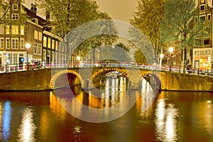 Picturesque Night View of Amterdam Cityscape with One The Canals Along With Illuminated Bridge and Traditional Dutch Houses At