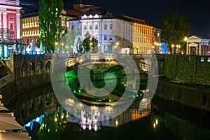 Picturesque night view of illuminated Triple Bridge and Mayer Palace in Ljubljana, Slovenia