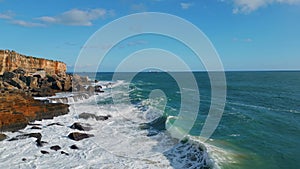 Picturesque ocean swell rolling on rocky seashore sunny day. Aerial stormy sea