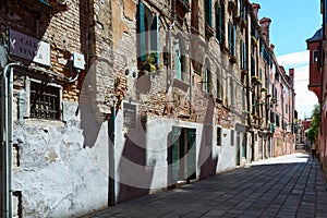 Picturesque old facade of building in Venice, Italy. Details of aged brick wall with windows deorated with plants