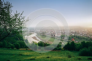 Picturesque outdoor scene on mountain valley, river and small village in morning fog at sunrise. Location - Carpathian