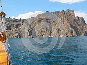 A picturesque panorama of the impregnable cliffs of the extinct volcano Karadag from the side of a pleasure yacht against a bright