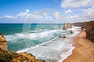 Picturesque panorama photo card on stunning views of ocean waves, orange sandy beach and steep cliffs under blue sky The Twelve