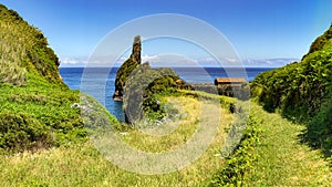 Picturesque panorama with a small picnic area by the sea with rocks and a green meadow