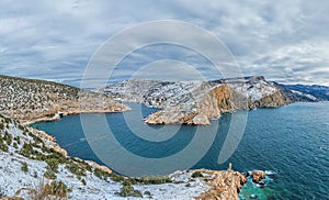 A picturesque panoramic view of the winter snow-covered Balaklava Bay, the ruins of the Genoese fortress Chembalo