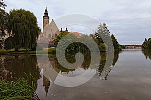 A picturesque park with a lake near the castle of Telc. Ancient buildings at the background. Summer landscape photo