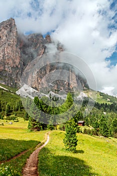 Picturesque path on a high alpine meadow with misty peaks of Italian Dolomites.
