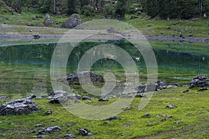 Picturesque peaks of Dolomites mountains in reflection of crystal clear pond surrounded by coniferous forest. Lake of Caresse in