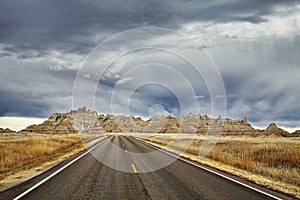 Picturesque road in Badlands National Park with stormy sky.