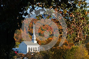 Picturesque scene of a church in Vermont, with brightly colored autumn foliage in the background