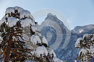 Picturesque snow-capped rocks against the blue sky. The inaccessible mountains are covered in snow during a severe blizzard. Rock