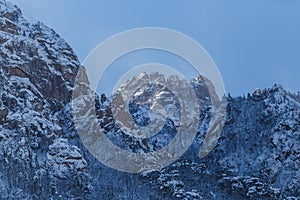 Picturesque snow-capped rocks against the blue sky. The inaccessible mountains are covered in snow during a severe blizzard. Rock